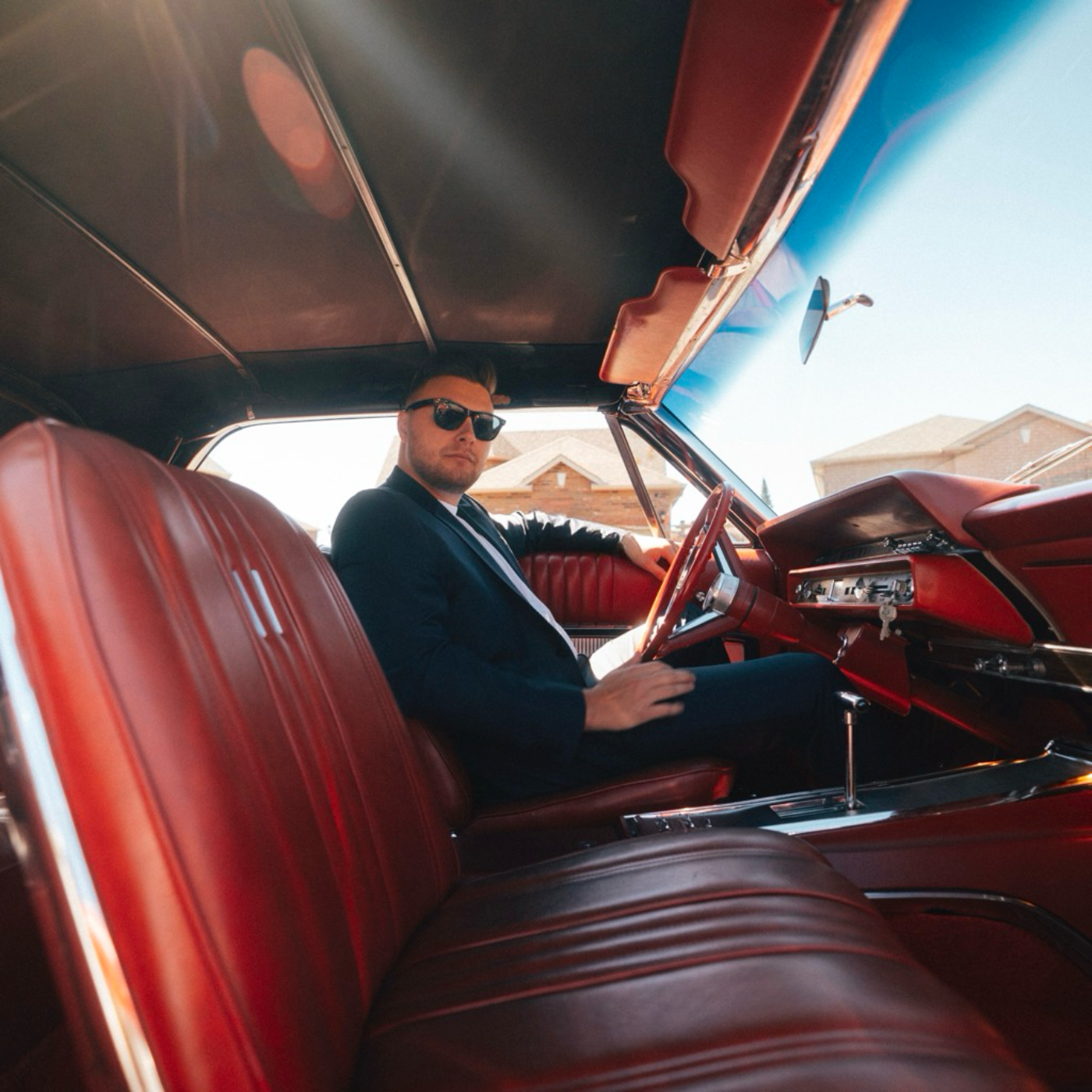 Nicholas Petrungaro inside a classic red car on the Too Comfortable single cover